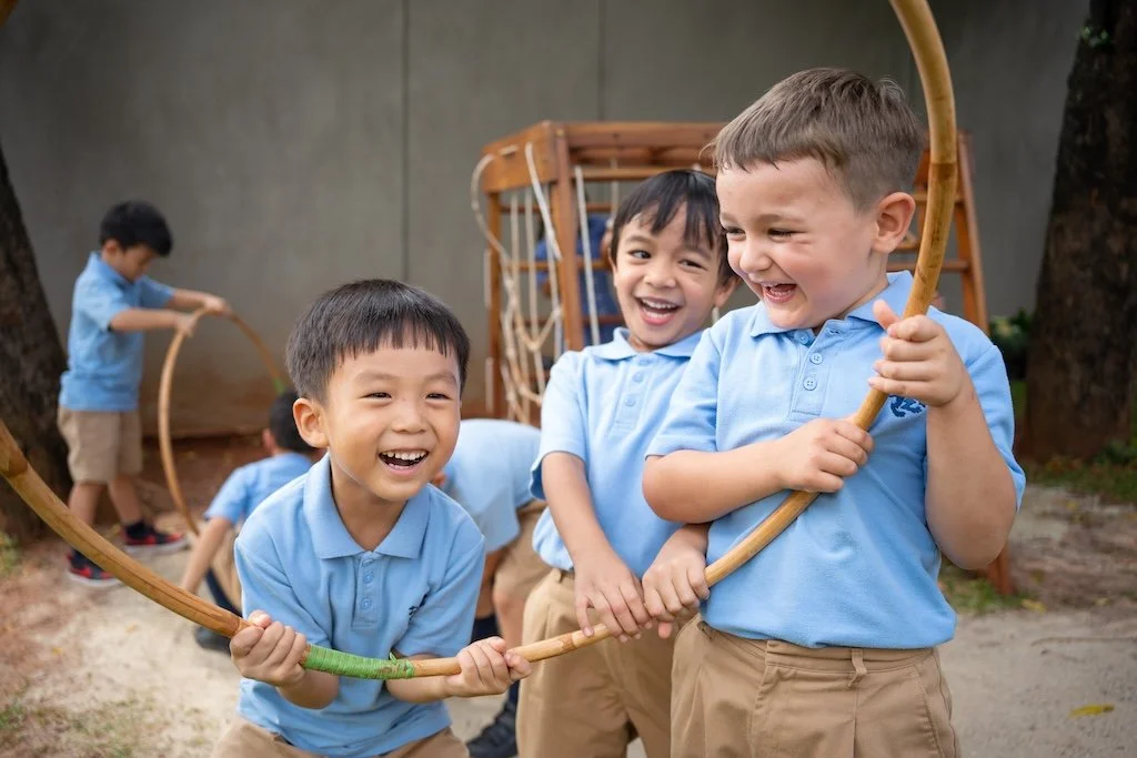 Three boys in blue polo shirts laughing together at ISJ