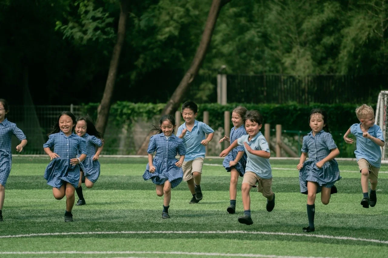 Children running happily on the grass at ISJ
