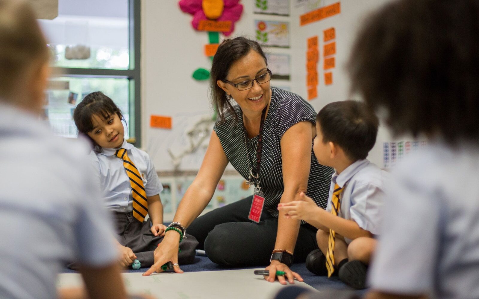 An ISJ teacher working with young pupils on the classroom floor